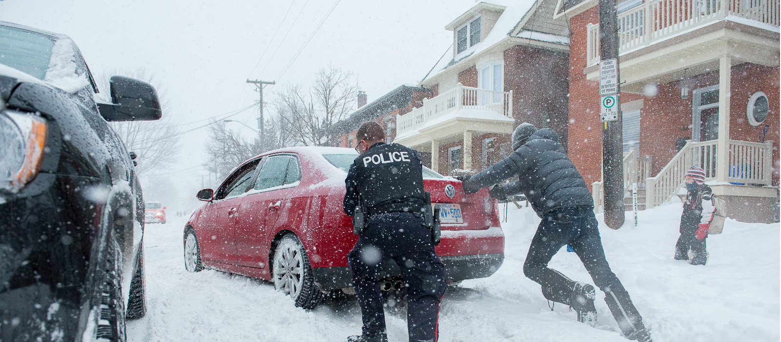 Community Police Officer help a resident out during a winter storm by pushing his stuck car