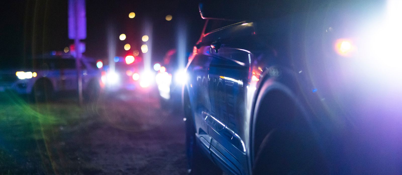Several stopped police cruisers with their lights flashing at night.